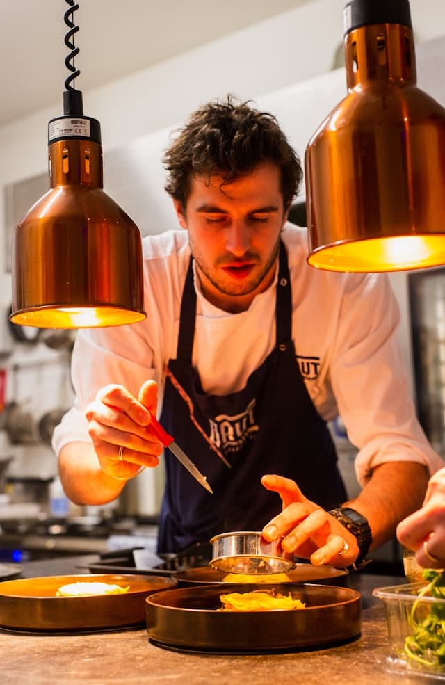 Close-up of a chef's hands carefully plating a dish with tweezers