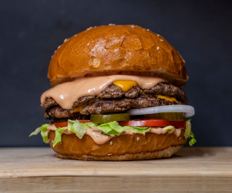 Close-up of a flame-grilled smash burger with melted cheese dripping down the sides